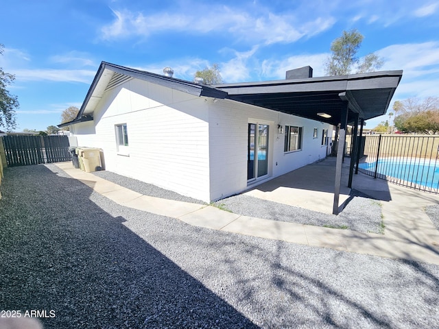 view of side of home featuring a patio, fence, and a fenced in pool