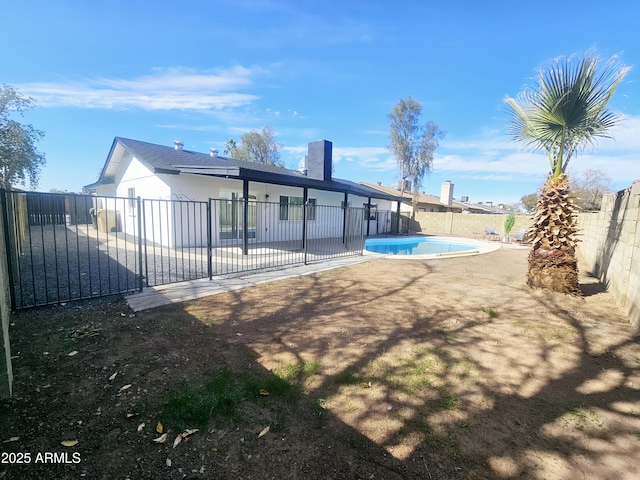 rear view of house featuring a fenced backyard, a fenced in pool, and a patio