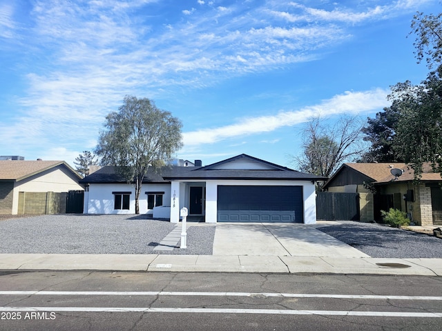 view of front of property featuring driveway, an attached garage, fence, and stucco siding