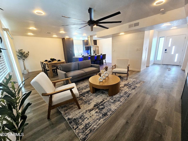 living area with dark wood-style floors, baseboards, and visible vents