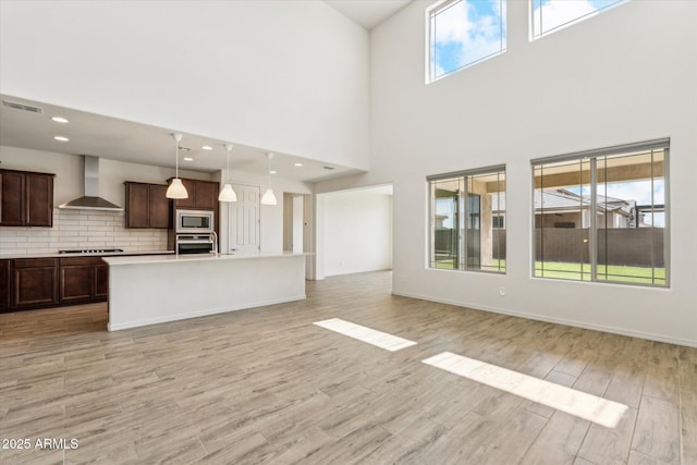 22987 E Pummelos Rd, Queen Creek, AZ 85142 - kitchen featuring wall chimney range hood, visible vents, appliances with stainless steel finishes, light wood finished floors, and backsplash