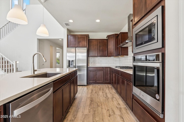 22987 E Pummelos Rd, Queen Creek, AZ 85142 - kitchen featuring visible vents, a sink, wall chimney range hood, appliances with stainless steel finishes, and decorative backsplash