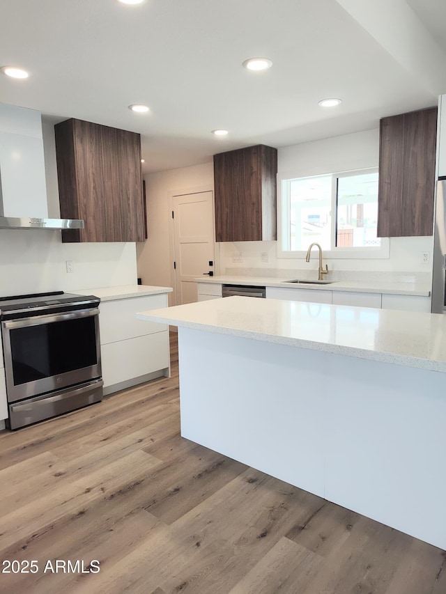 1920 N Cavalier Dr, Tempe, AZ 85288 - kitchen with stainless steel appliances, wall chimney exhaust hood, modern cabinets, a sink, and light wood-style flooring