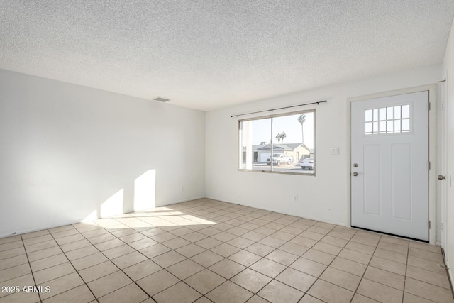 foyer entrance featuring a textured ceiling and light tile patterned floors