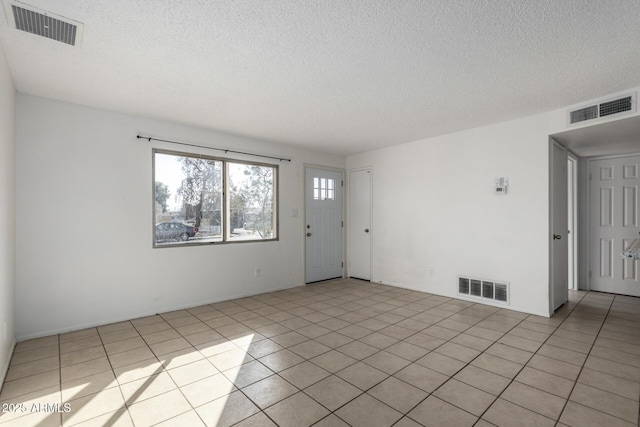 unfurnished room with a textured ceiling and light tile patterned floors