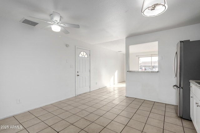 interior space featuring white cabinetry, light tile patterned floors, stainless steel fridge, and ceiling fan