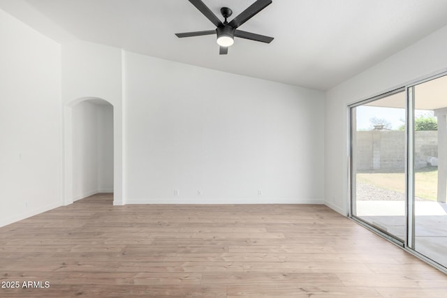 spare room featuring light wood-style flooring, arched walkways, baseboards, and a ceiling fan