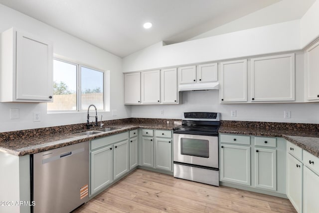 kitchen featuring appliances with stainless steel finishes, light wood-style flooring, under cabinet range hood, lofted ceiling, and a sink
