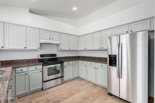 kitchen featuring dark stone countertops, recessed lighting, under cabinet range hood, light wood-style floors, and stainless steel appliances