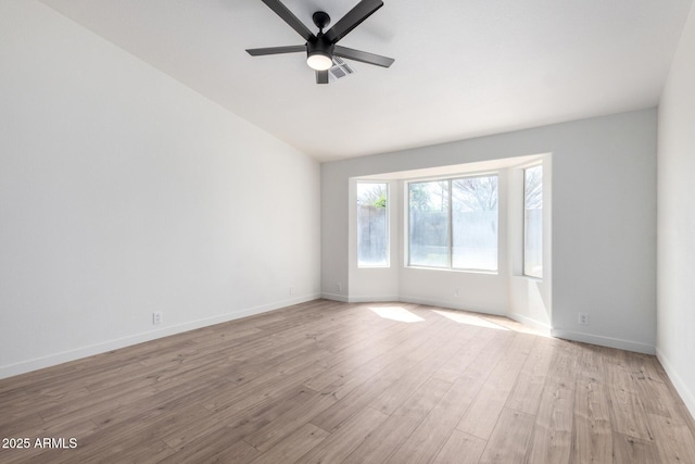 unfurnished room with visible vents, baseboards, ceiling fan, vaulted ceiling, and light wood-style flooring