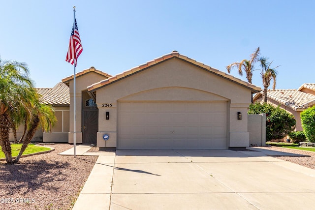 ranch-style home featuring a tile roof, stucco siding, a garage, and concrete driveway
