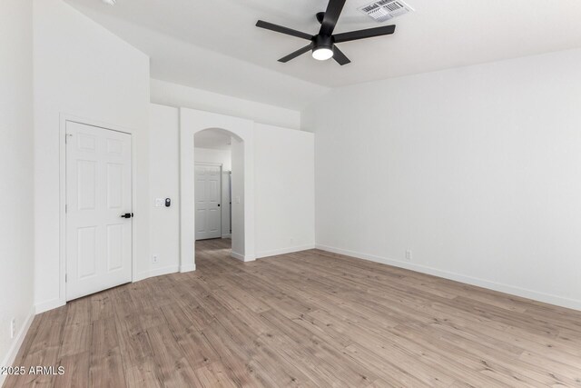 interior space with ceiling fan, arched walkways, light wood-type flooring, visible vents, and baseboards