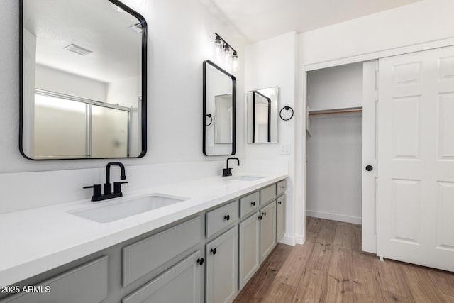 bathroom with double vanity, visible vents, a sink, and wood finished floors