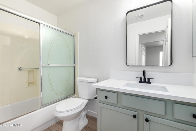 bathroom featuring vanity, toilet, visible vents, bath / shower combo with glass door, and wood finished floors