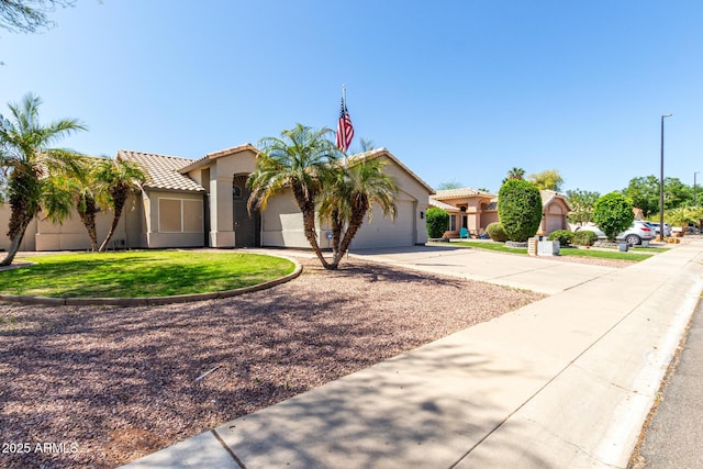 mediterranean / spanish-style house with a tiled roof, an attached garage, driveway, and stucco siding