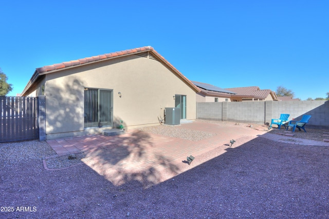 rear view of house featuring cooling unit, a patio area, and solar panels