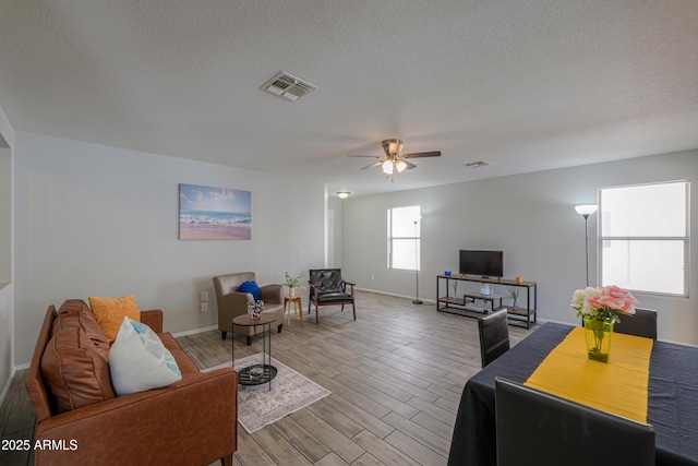 living room featuring ceiling fan, wood-type flooring, and a textured ceiling