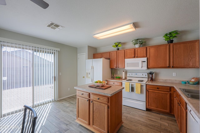 kitchen featuring white appliances, sink, a kitchen island, and a textured ceiling