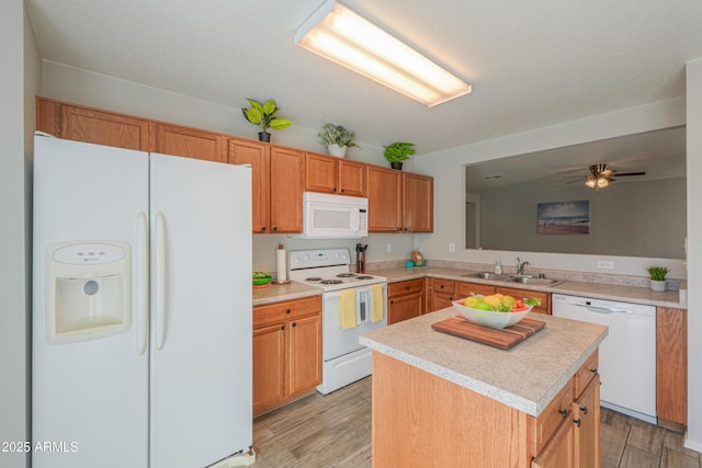 kitchen with white appliances, sink, light hardwood / wood-style floors, and a kitchen island