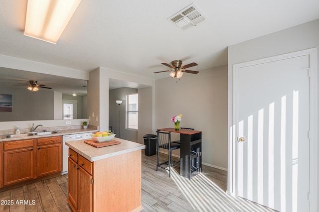 kitchen featuring dishwasher, sink, a center island, ceiling fan, and light hardwood / wood-style floors