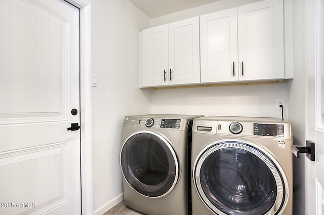 clothes washing area with cabinets and washing machine and clothes dryer