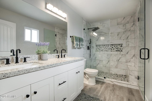 bathroom with hardwood / wood-style flooring, toilet, vanity, and a shower with shower door