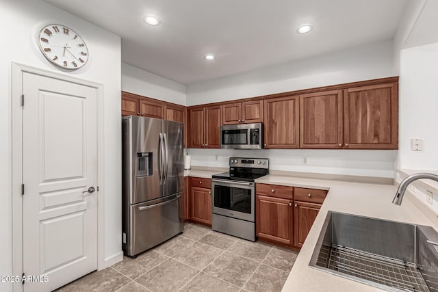 21472 E Saddle Ct, Queen Creek, AZ 85142 - kitchen featuring appliances with stainless steel finishes, a sink, light countertops, brown cabinetry, and recessed lighting