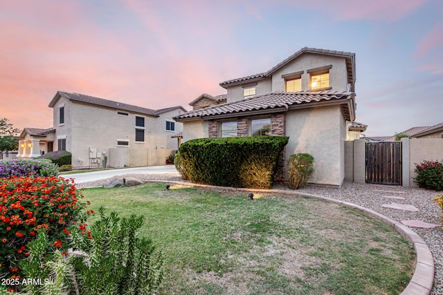 21472 E Saddle Ct, Queen Creek, AZ 85142 - back of property at dusk featuring a gate, stucco siding, a tiled roof, and a lawn