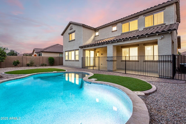 21472 E Saddle Ct, Queen Creek, AZ 85142 - back of house at dusk with stucco siding, a tiled roof, a fenced backyard, and a patio area