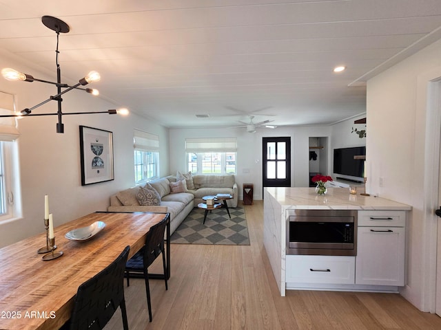 kitchen with white cabinetry, visible vents, open floor plan, light wood finished floors, and stainless steel microwave