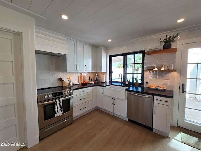 kitchen featuring dark countertops, custom range hood, stainless steel appliances, white cabinetry, and open shelves