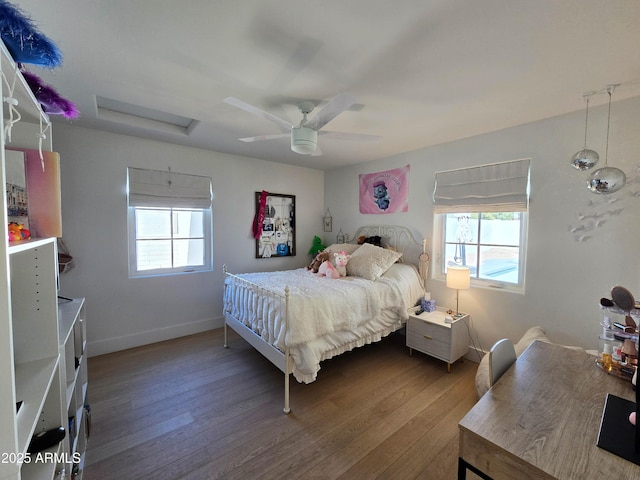 bedroom featuring attic access, multiple windows, baseboards, and wood finished floors