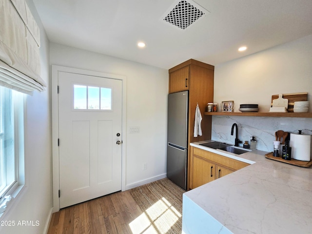 kitchen featuring open shelves, light countertops, visible vents, freestanding refrigerator, and a sink