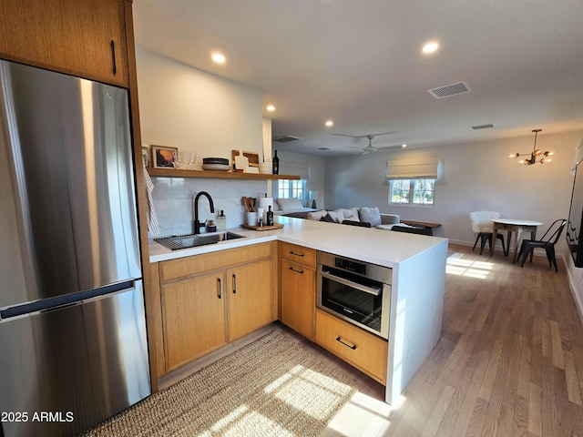 kitchen featuring stainless steel appliances, open floor plan, a sink, and a peninsula