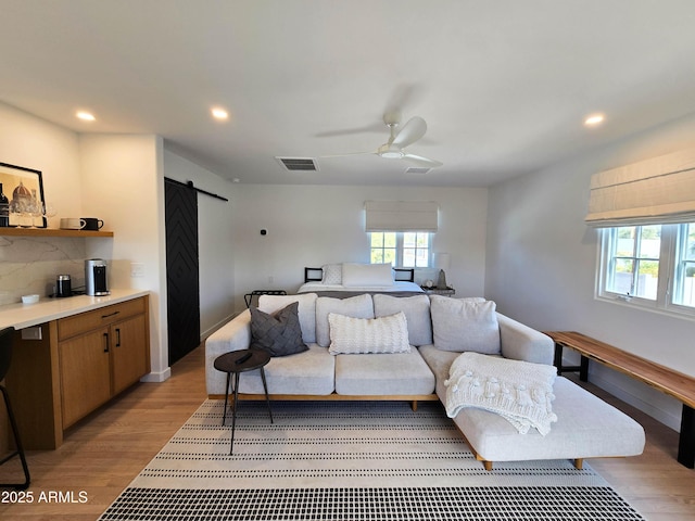 bedroom with recessed lighting, visible vents, light wood-style flooring, and a barn door