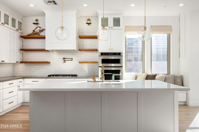 kitchen with decorative backsplash, double oven, decorative light fixtures, light hardwood / wood-style floors, and white cabinetry