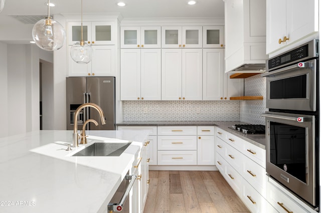 kitchen with pendant lighting, light stone countertops, light wood-type flooring, white cabinetry, and stainless steel appliances