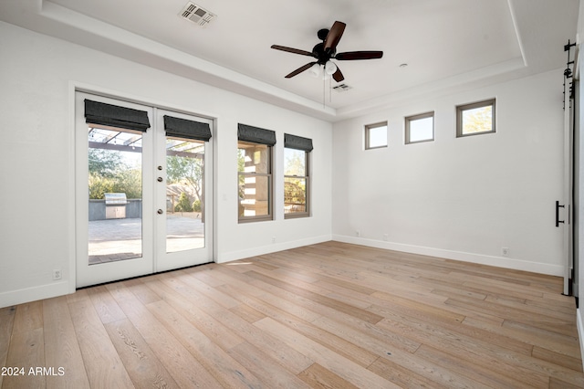 spare room featuring french doors, a tray ceiling, ceiling fan, and light hardwood / wood-style floors