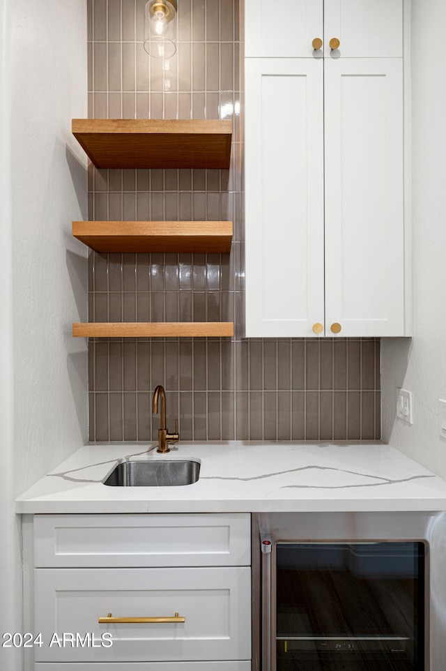 bar featuring tasteful backsplash, light stone counters, sink, and beverage cooler