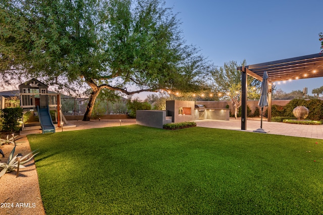 yard at dusk featuring a playground, area for grilling, a pergola, and a patio area