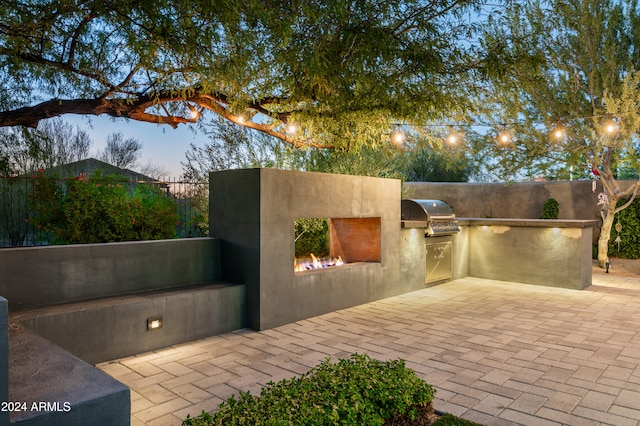 patio terrace at dusk with a grill and exterior kitchen