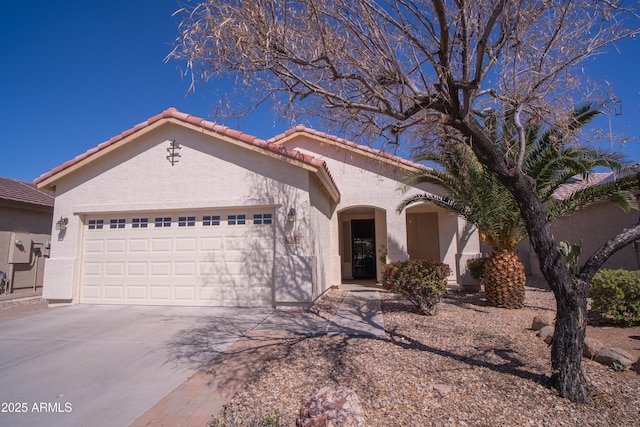 mediterranean / spanish-style home with stucco siding, a garage, concrete driveway, and a tile roof