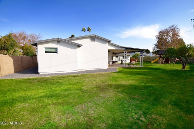 rear view of property featuring a yard, a patio, ceiling fan, and a playground