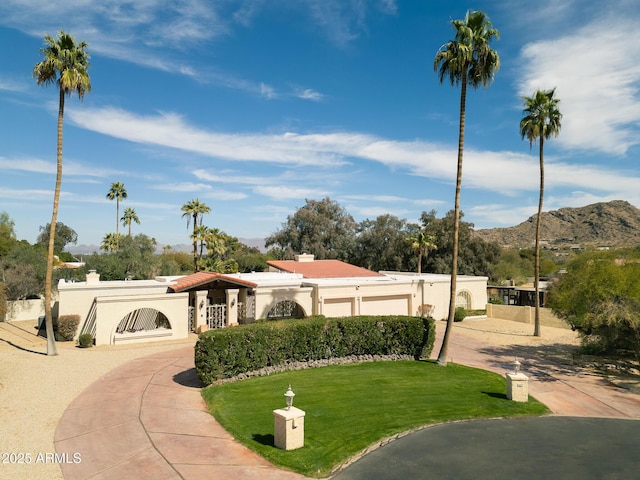 view of front of home featuring an attached garage, a mountain view, stucco siding, a chimney, and a front yard