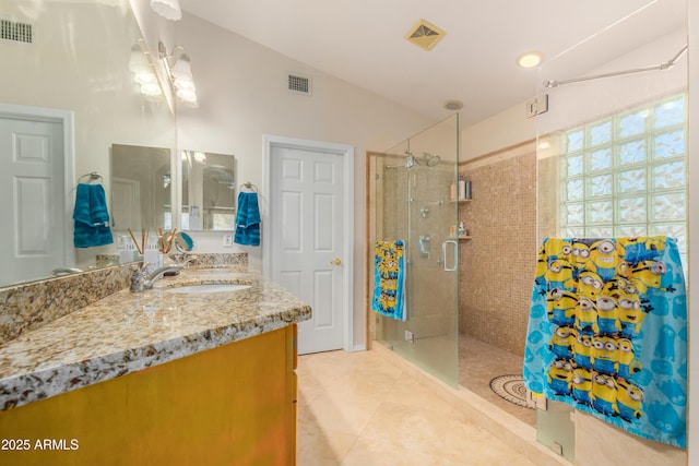 bathroom with a shower with door, vanity, and tile patterned flooring