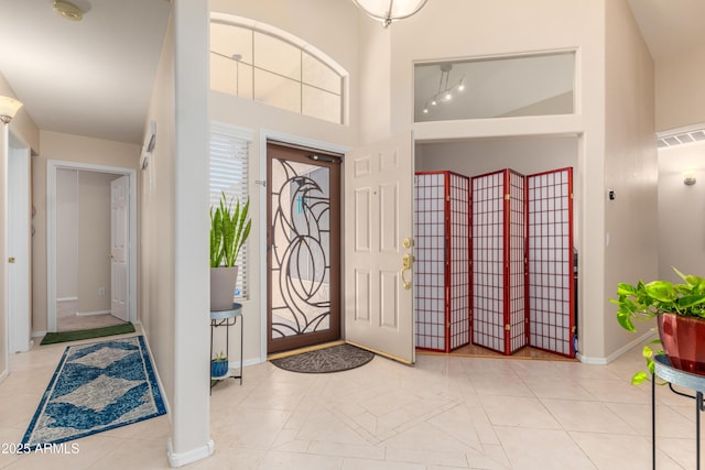 entrance foyer with light tile patterned flooring and a towering ceiling