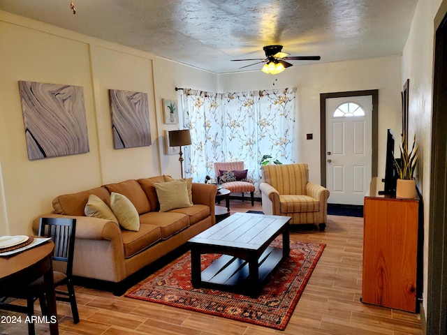 living room featuring a textured ceiling, light hardwood / wood-style floors, and ceiling fan