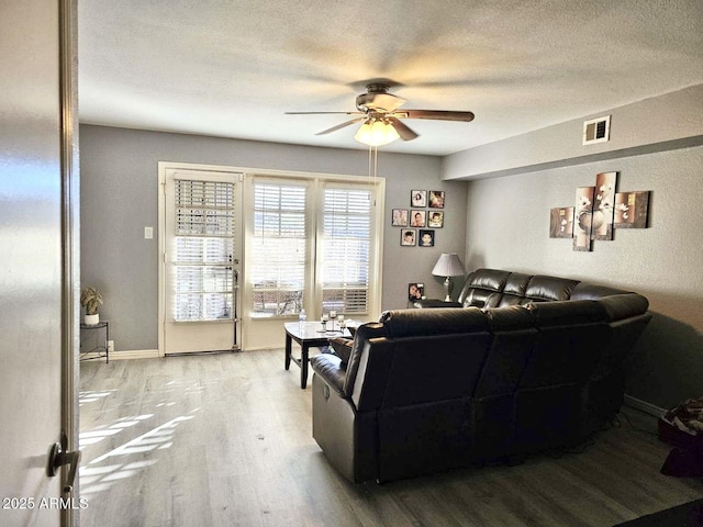 living room with ceiling fan, light hardwood / wood-style flooring, and a textured ceiling