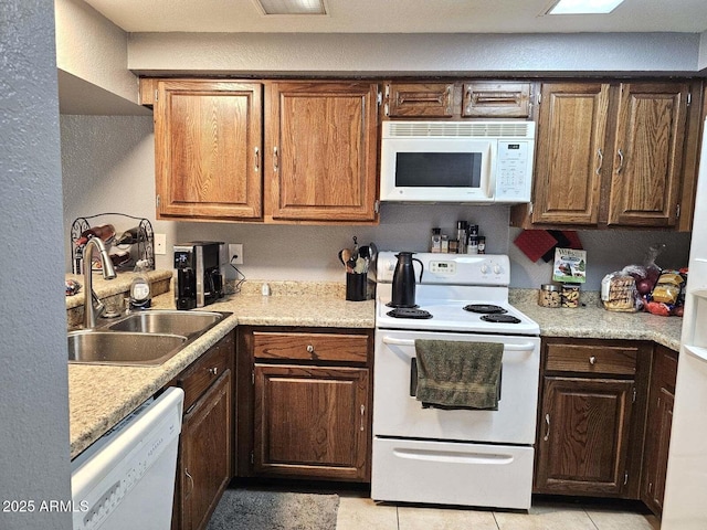 kitchen featuring light tile patterned flooring, white appliances, and sink