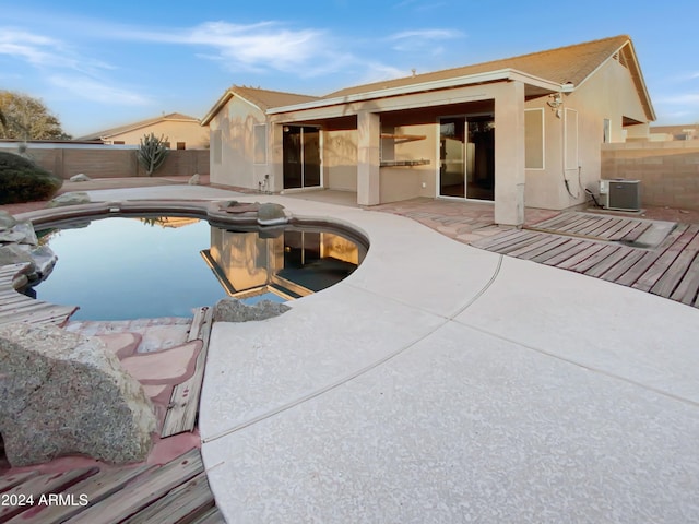 rear view of house with cooling unit, a fenced in pool, and a patio